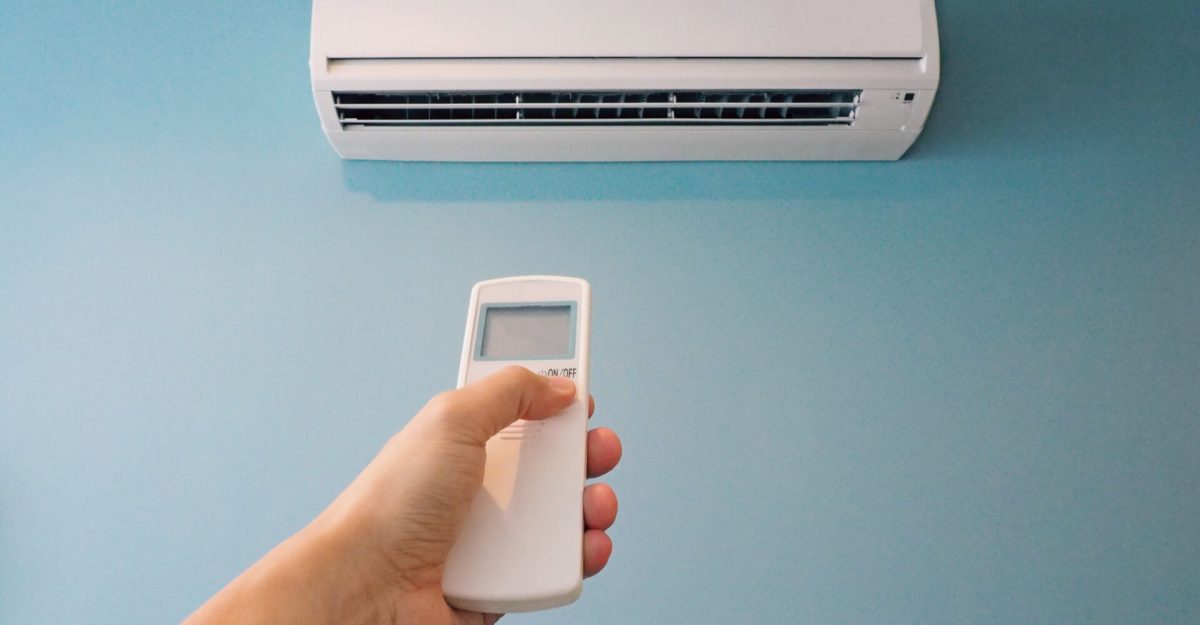 Man pressing button on air conditioner remote control after using to save power and cost