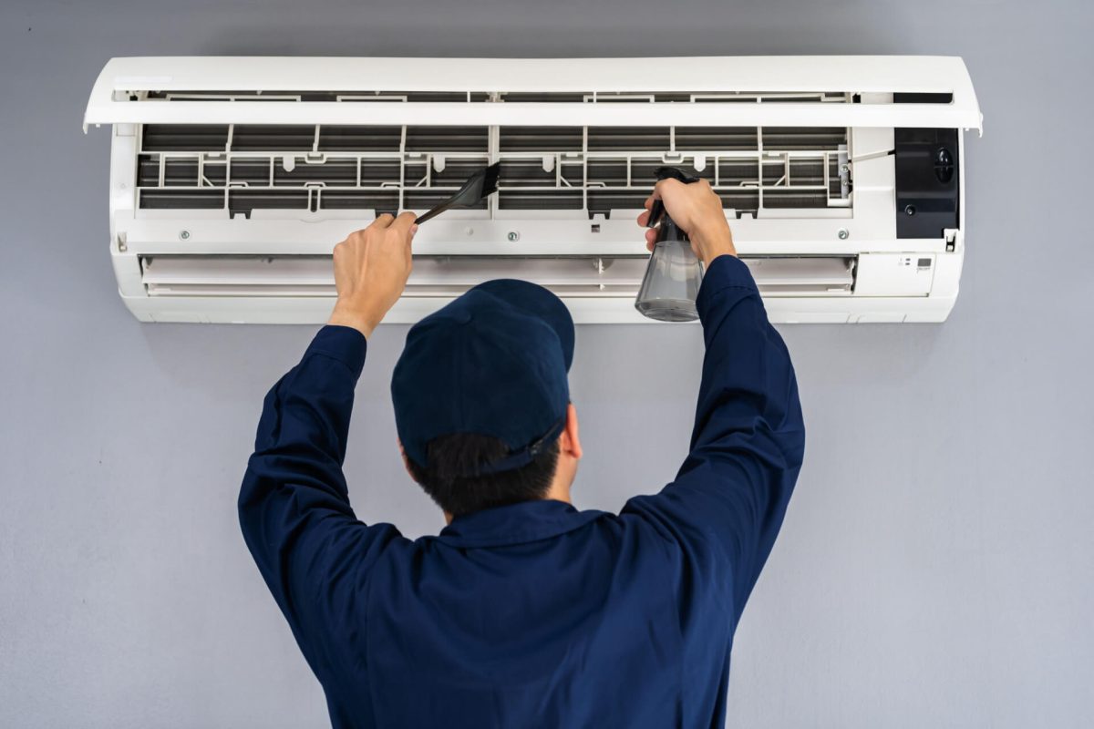 Technician lifting air conditioning cover for maintenance.