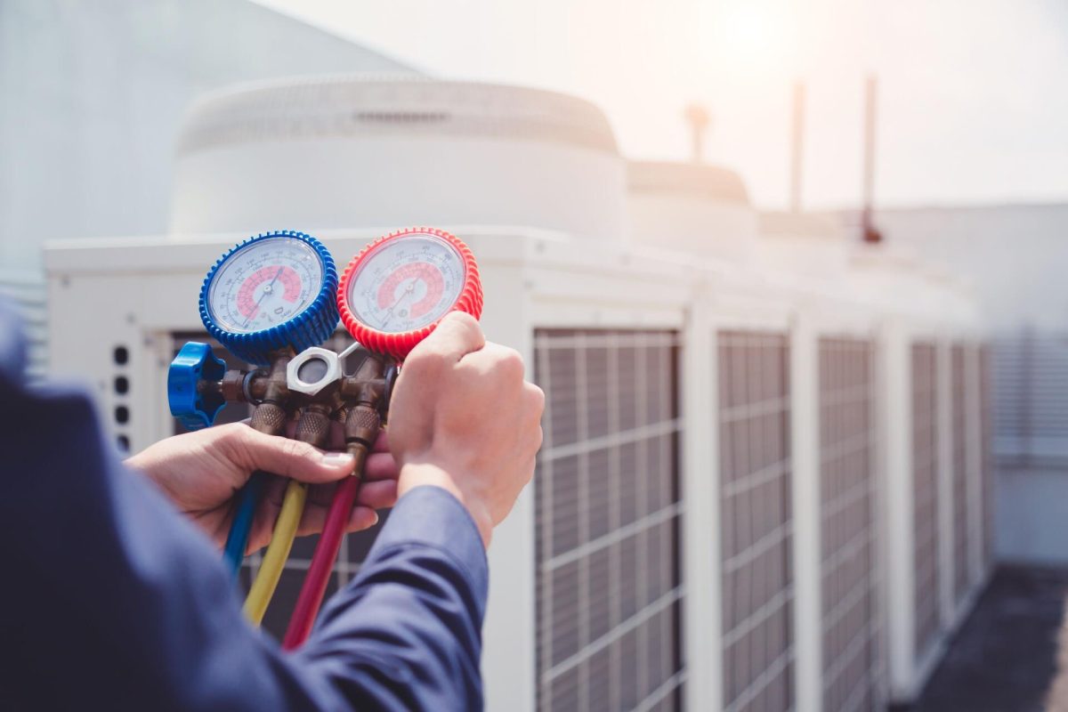 Technician using HVAC manifold gauge to measure system pressure.