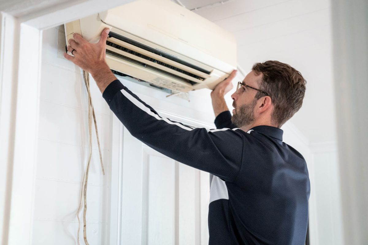 Technician mounting a split system unit on an interior wall.