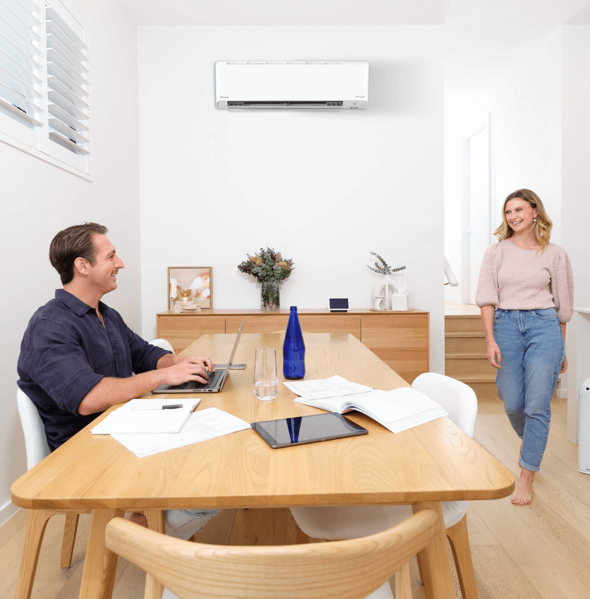 Couple discussing air conditioning options at a dining table beneath a mounted unit.