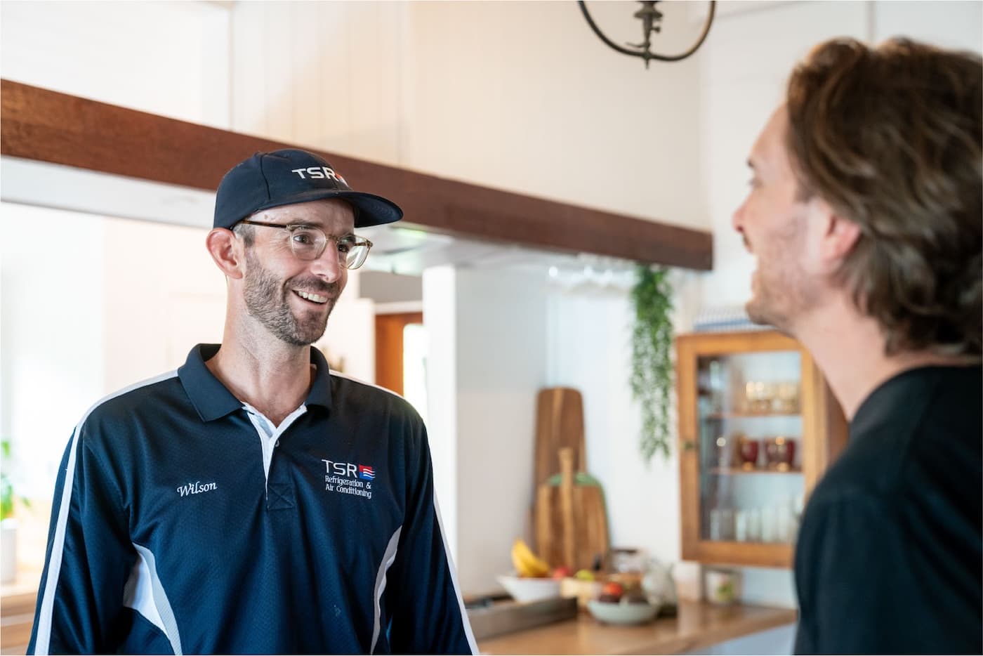 TSR technician smiling and speaking with a homeowner in their kitchen.