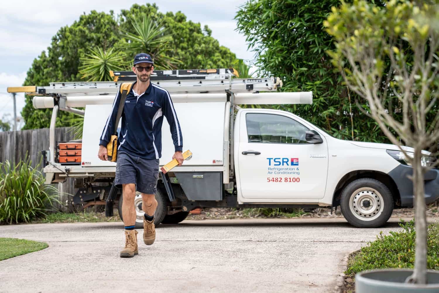 Technician walking to van with tools in hand outside TSR HQ.